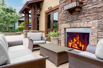 A patio with a fireplace and chairs.